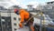 Industrial climber in suit checks and sets rope insurance on roof of building before descent