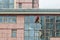 An industrial climber washes windows at a high altitude of a large office building