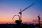 Industrial construction cranes and building silhouettes at sunrise or sunset