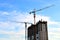 Industrial construction cranes and silhouettes of workers during installation of formwork