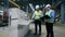 Industrial control panel and two engineers talking near it in a modern factory floor.