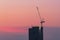 Industrial crane at construction site with sunset sky