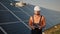 Industrial expert wearing helmet and controlling drone in photovoltaic solar power plant. Solar panel array installation