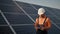 Industrial expert wearing helmet and controlling drone in photovoltaic solar power plant. Solar panel array installation