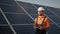 Industrial expert wearing helmet and controlling drone in photovoltaic solar power plant. Solar panel array installation