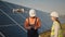 Industrial expert wearing helmet and controlling drone in photovoltaic solar power plant. Solar panel array installation