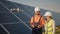 Industrial expert wearing helmet and controlling drone in photovoltaic solar power plant. Solar panel array installation