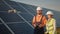 Industrial expert wearing helmet and controlling drone in photovoltaic solar power plant. Solar panel array installation