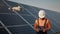 Industrial expert wearing helmet and controlling drone in photovoltaic solar power plant. Solar panel array installation