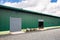 Industrial facade, metal door of warehouse.  Grey door with green wall