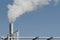 Industrial fog from exhaust tube against blue sky background