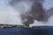 Industrial harbor with many vessels and black smoke rising