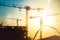 Industrial heavy duty construction site with tower cranes and building silhouettes