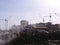 Industrial industrial landscape construction site with a crane behind the white smoke fumes from the excavated heating main