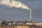 Industrial landscape. Factory smokestack and white smoke against the blue sky