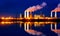 Industrial landscape with smoking chimneys and reflection in water at night