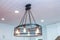 An industrial lighting fixture with Edison bulbs in an updated and remodeled all white modern kitchen