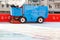An industrial machine cleans and polishes an ice rink in a stadium on a bright sunny day