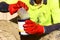 Industrial painter using red chemical safety protection glove while pouring harder from measuring cup back into paint bucket