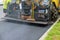 industrial pavement truck laying fresh asphalt on construction site