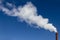 The industrial pipe produces white smoke in the blue sky. Concept Love Nature, Ecology and Technological Progress. Copy space.
