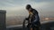 Industrial professional male climber stands on rooftop in uniform and unravels a safety rope for lowering down the wall