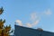 Industrial rooftop with pipe venting steam in early morning light against a blue sky