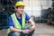 Industrial smiling worker wearing helmet holding radio walkie talkie at manufacturing plant factory industry, Asian young male