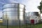 Industrial steel silos standing on the factory grounds on the lawn behind the fence.