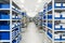 Industrial warehouse. White metal racks with blue plastic trays and cardboard boxes installed in them.