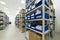Industrial warehouse. White metal racks with blue plastic trays and cardboard boxes installed in them.