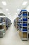 Industrial warehouse. White metal racks with blue plastic trays and cardboard boxes installed in them.