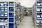 Industrial warehouse. White metal racks with blue plastic trays and cardboard boxes installed in them.