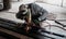 Industrial Worker at the factory welding closeup. Electric wheel grinding on steel structure in factory.