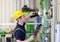 Industrial worker inspects and repairs a heating system in a factory - interior with pipelines and technology