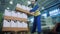 Industrial worker is stacking carton trays with plastic canisters