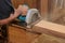 Industrial worker using circular miter saw for cutting wooden boards in carpentry workshop.