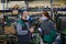 Industrial workers with face masks protected against corona virus discussing about production in factory. People working