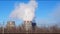 Industrial zone with large pipes cooling towers, with puffs of white dense smoke, the work of a thermal power station in a big cit