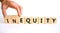 Inequity or equity symbol. Businessman turns wooden cubes and changes the word inequity to equity. Business and inequity or equity