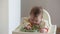 An infant 7-month caucasian girl is choosing the food with bare hands