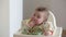 An infant 7-month caucasian girl is eating with bare hands