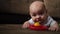 Infant baby boy lying on sofa with rattle toy.