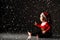 Infant baby boy toddler in red christmas cap and new year costume is sitting on ice under the snow looking at light ray