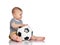 Infant baby boy toddler in striped t-shirt and pants is sitting holding football soccer ball playing on white