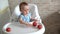 Infant baby eating apple. Cute little girl eating and playing apples in high chair. Adorable child tasting fruit. Healthy eating c