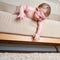 Infant baby falls off the sofa in the home living room. Toddler kid gets off the bed. Problems with the safety of children without
