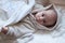 Infant baby girl in bed getting to sleep in bathrobe