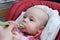 Infant baby girl in children chair eating meal