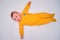 Infant baby lies on a play mat in yellow pajamas, top view. Toddler on the white floor full length, copy space